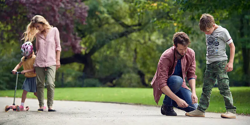 Man tying boys shoe lace